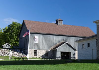 The Sheboygan County Museum's main building was designed to look like a carriage house with gray siding and a flag.